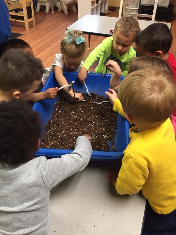 Children playing with dirt in a blue bin
