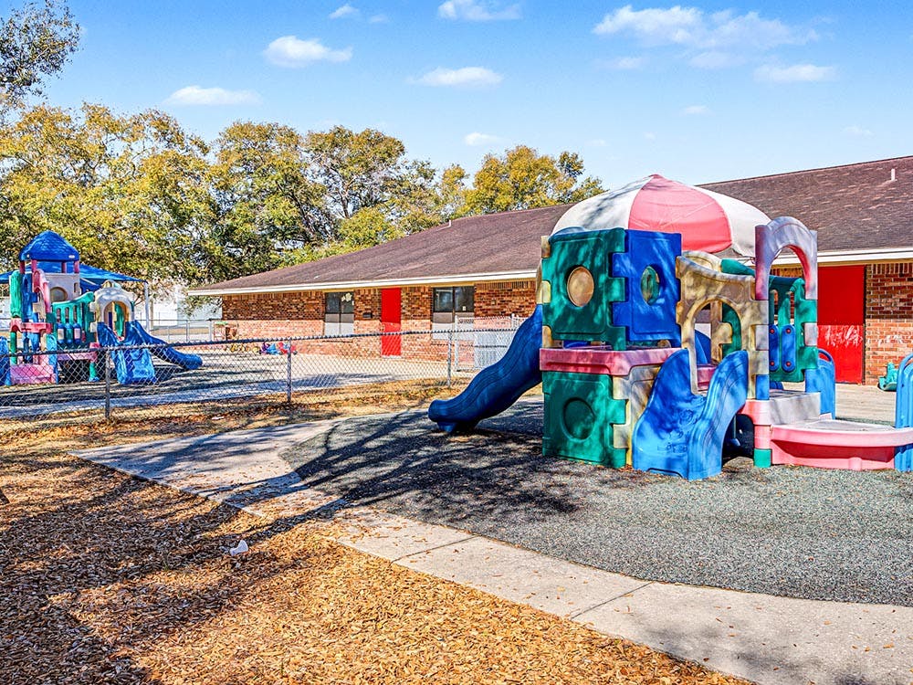 Colorful playgrounds on wood chips and rubber flooring outside a building