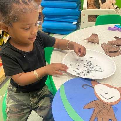 Child picking up googly eyes from a plate for crafting