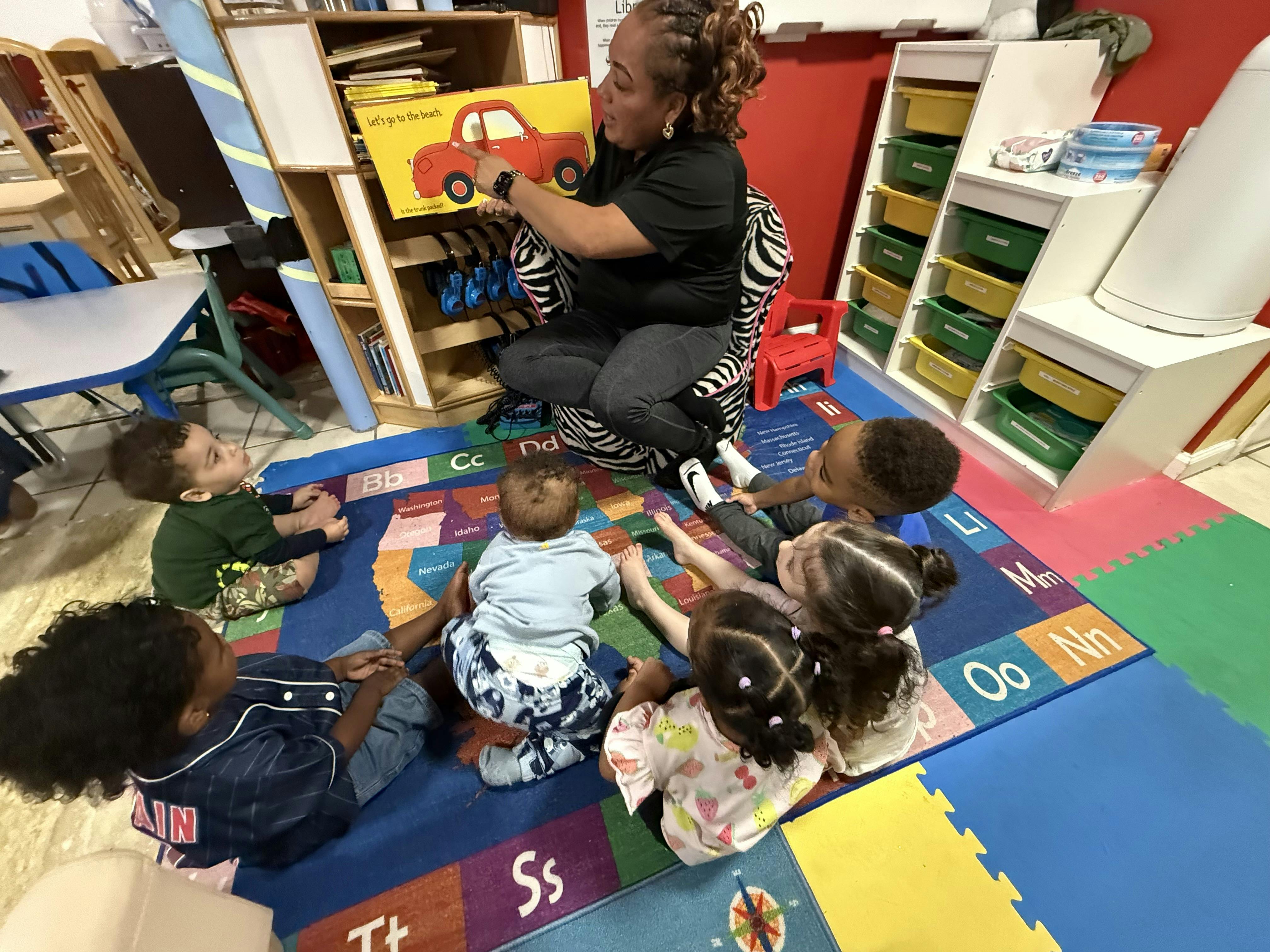 Person reading a book to several children in a classroom