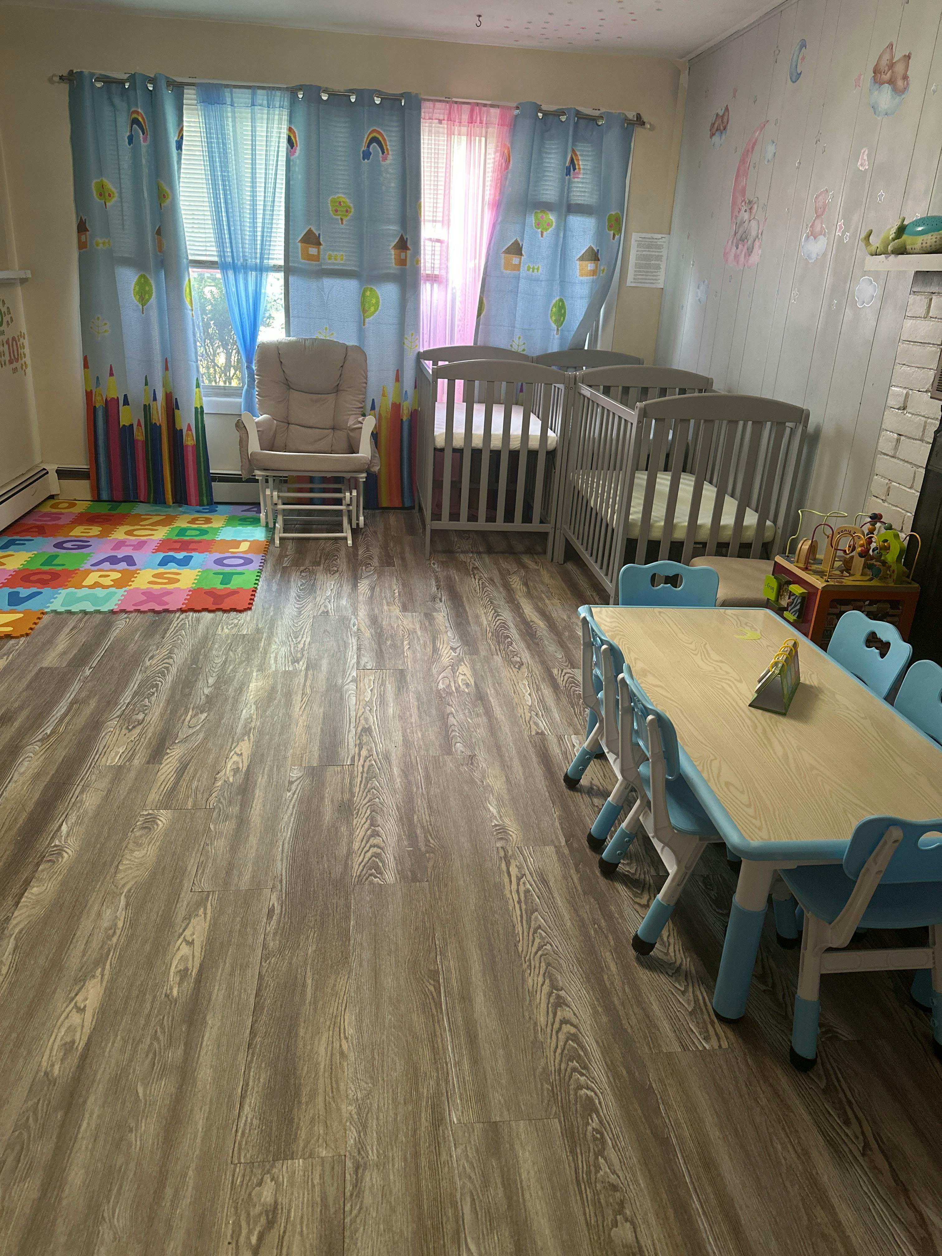 Nursery room with two cribs, a rocking chair, and a child-sized table with chairs