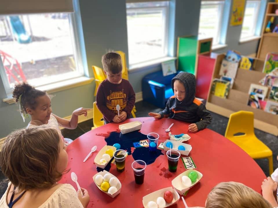 Children at a red table with cups and craft supplies