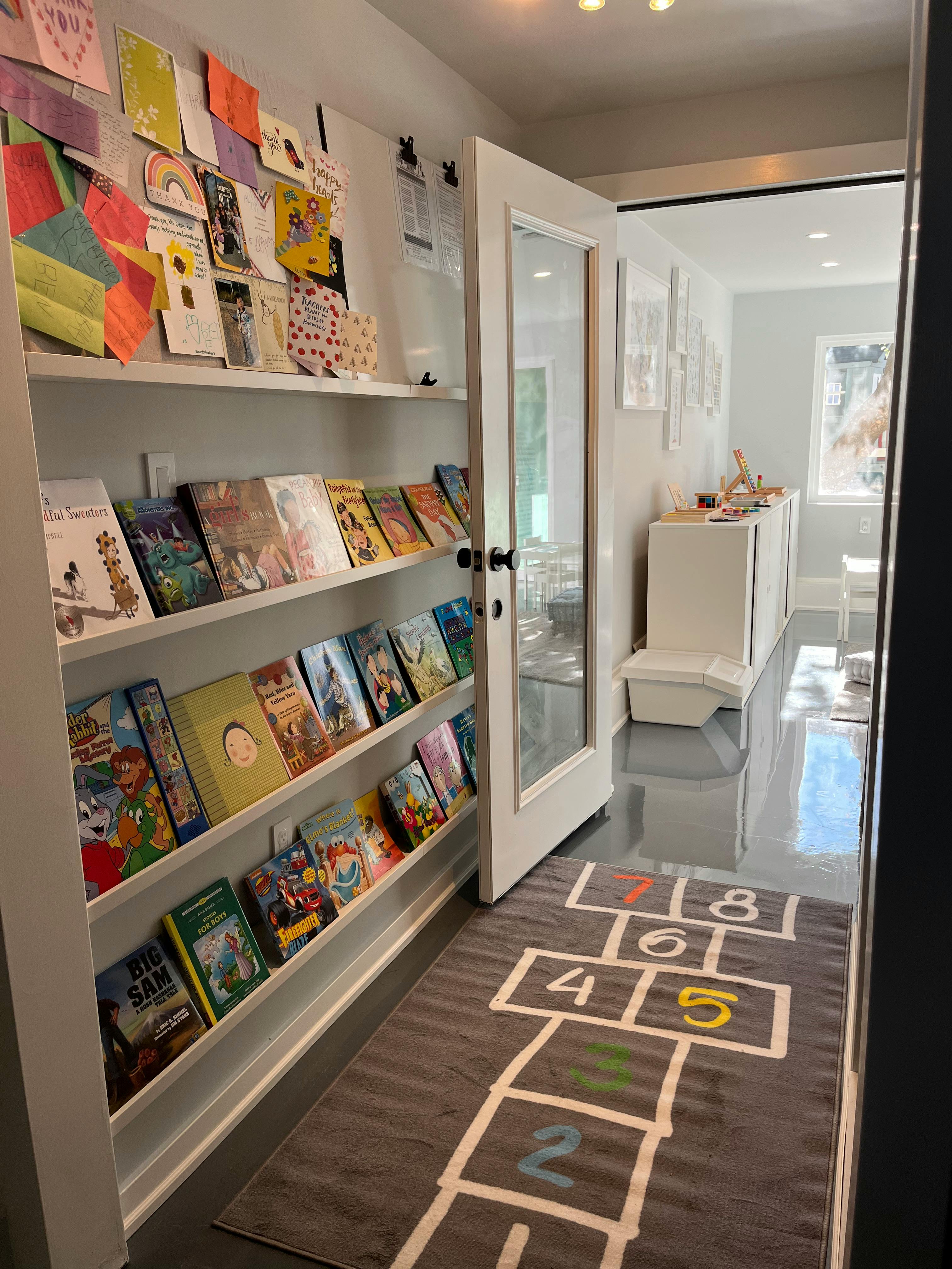 Bookshelves with books and a hopscotch rug in a hallway