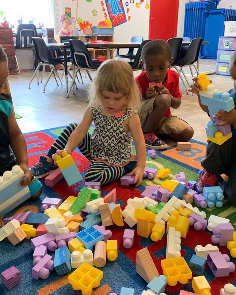Children playing with colorful building blocks on a rug