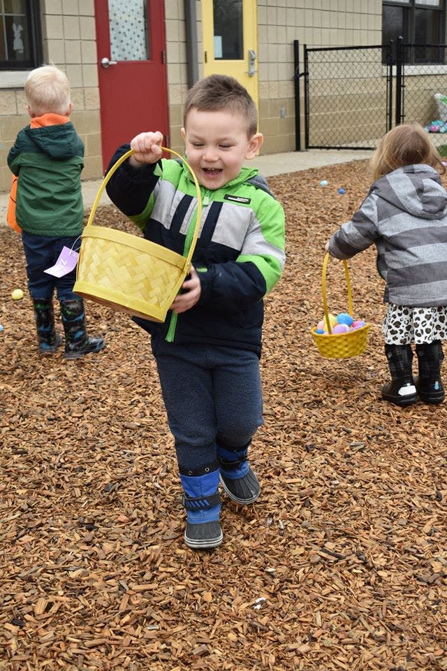 Child holding a yellow basket on a playground