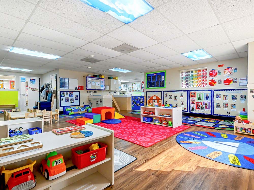 Colorful and organized empty daycare classroom with toys, rugs, and small tables