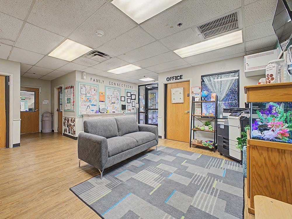 Waiting room with a gray couch, a patterned rug, and a fish tank