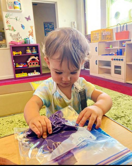 Child playing with a plastic bag on a table