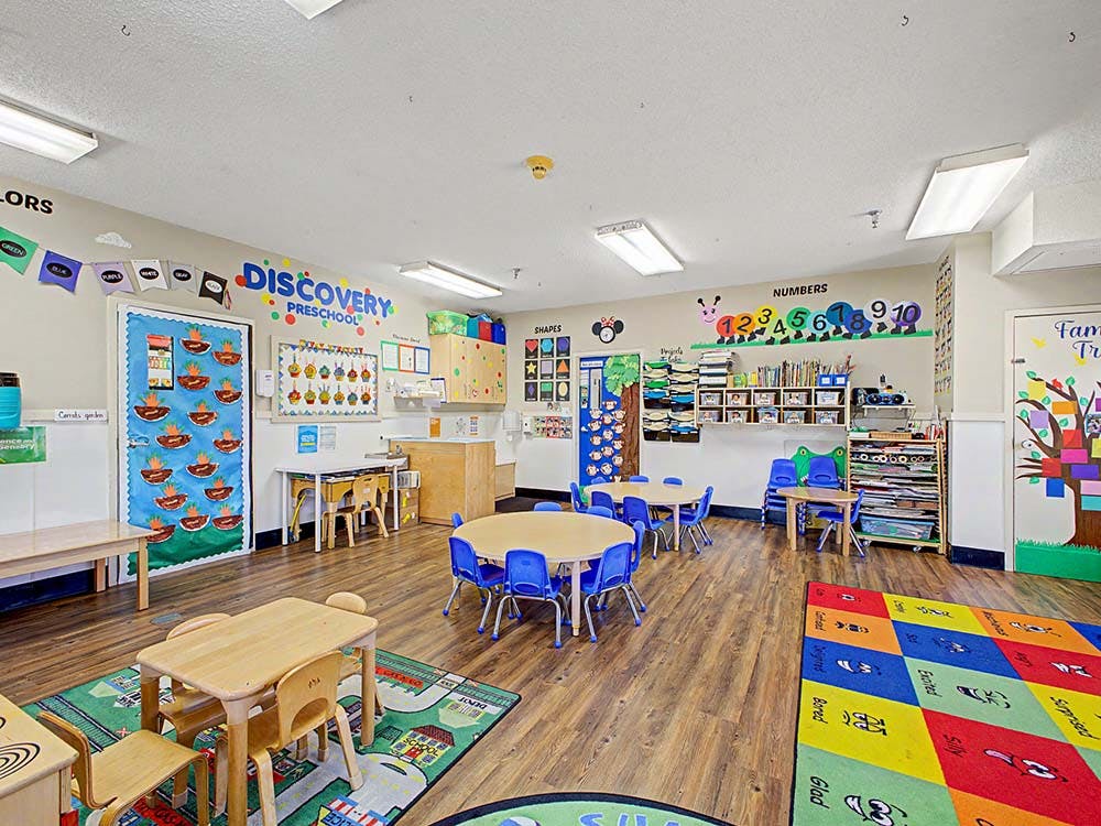 Colorful empty preschool classroom with small tables and chairs