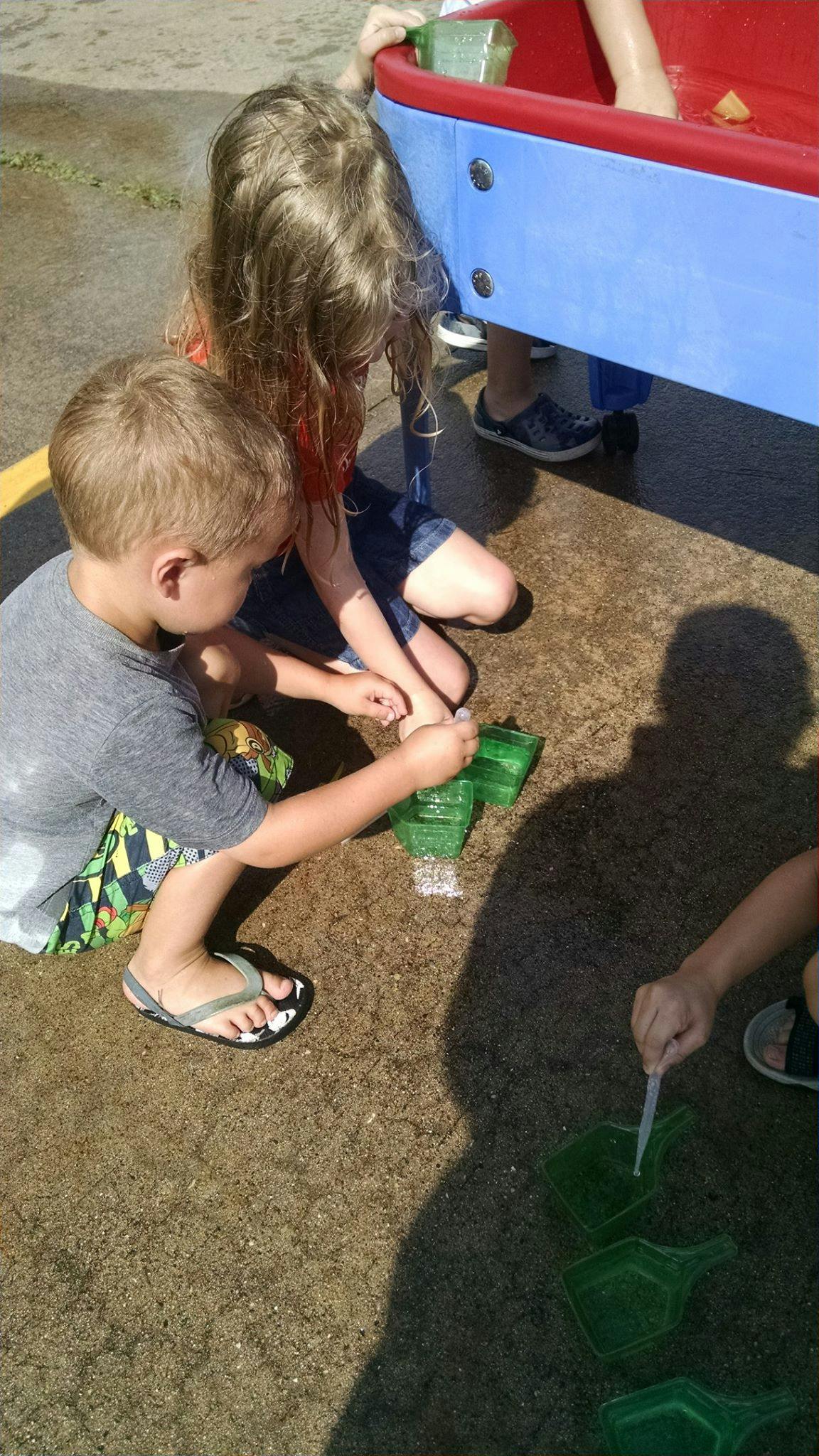 Children playing with water and toys outdoors