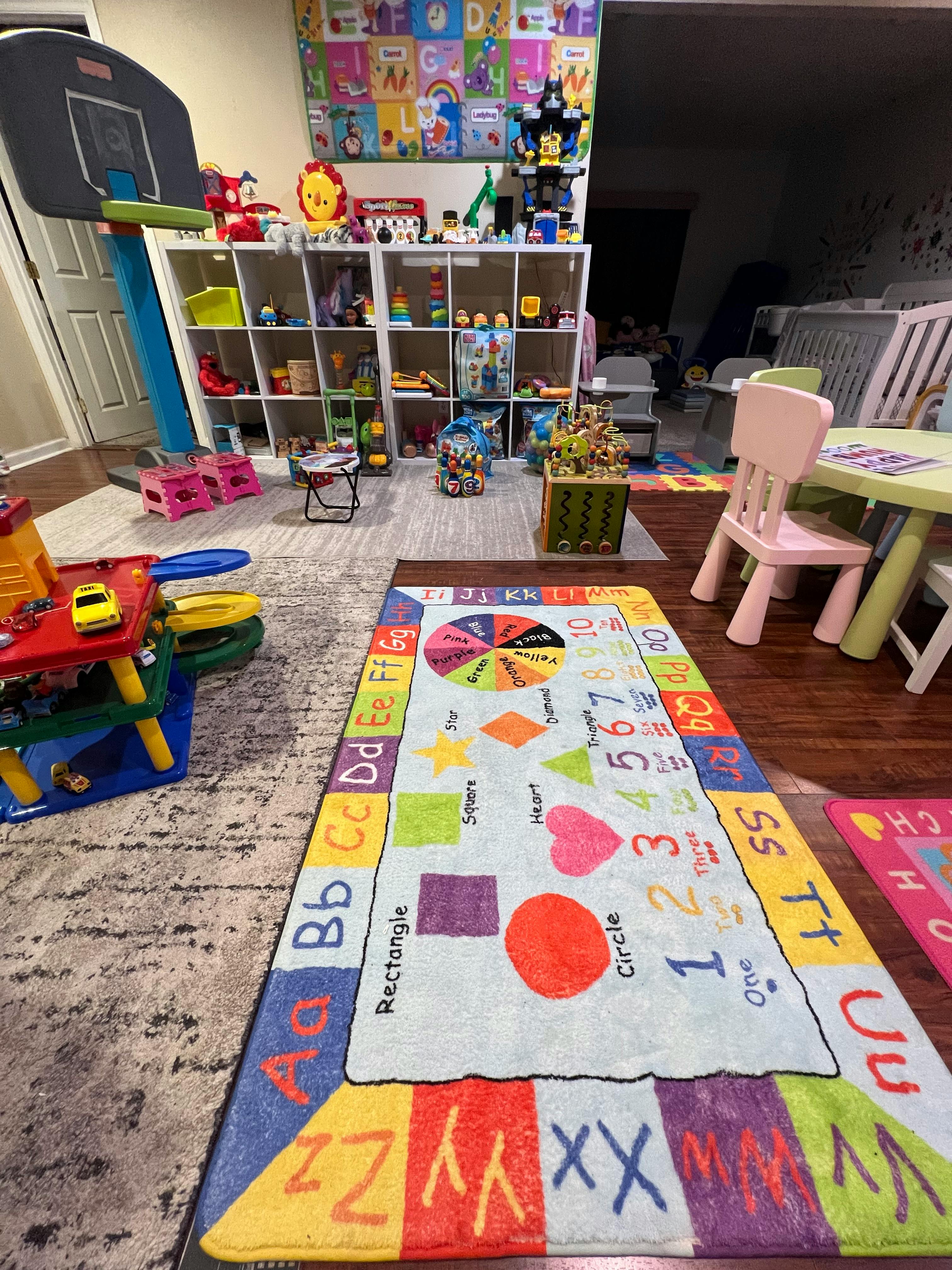 Playroom with a colorful alphabet and numbers rug, toys, and small chairs
