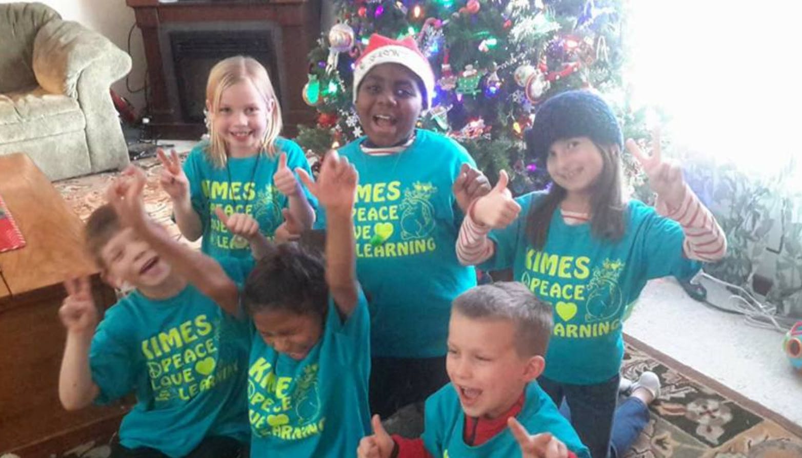 Group of children in matching shirts making hand gestures
