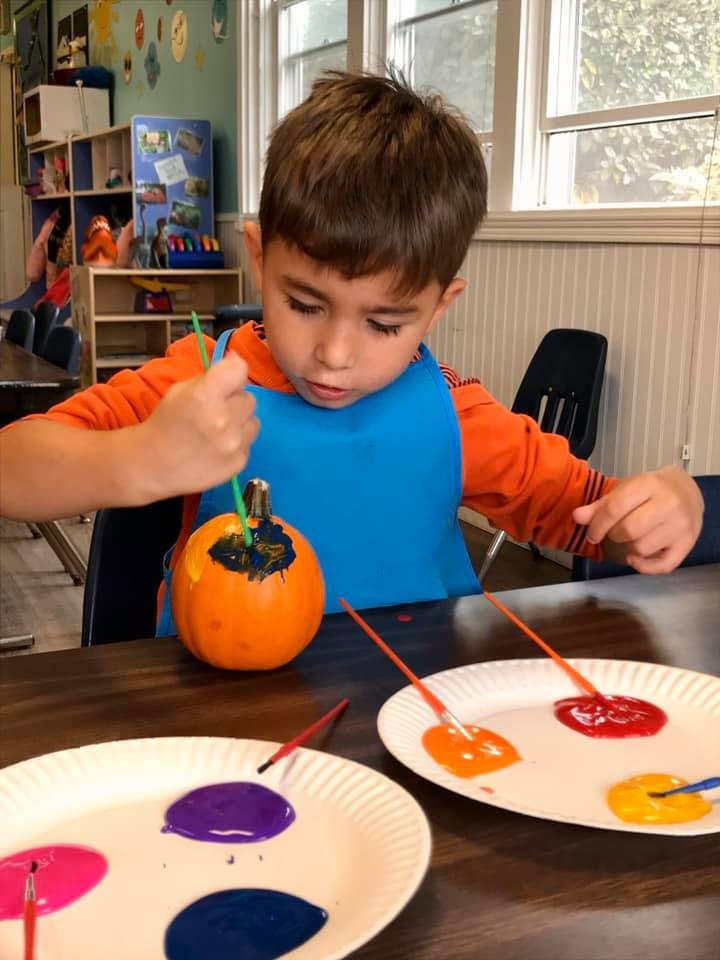 Child painting a small pumpkin with a brush