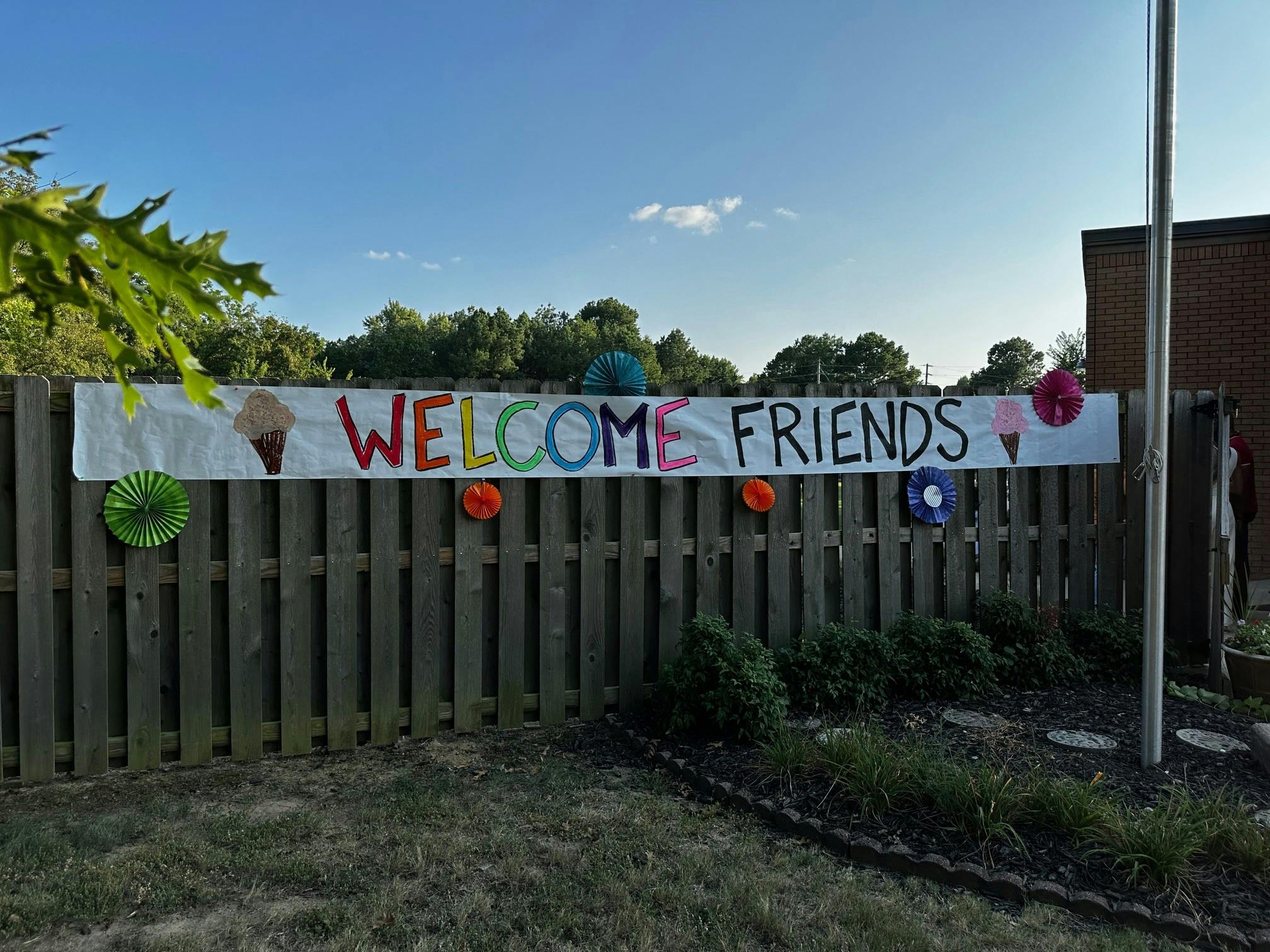 Welcome Friends banner on a wooden fence