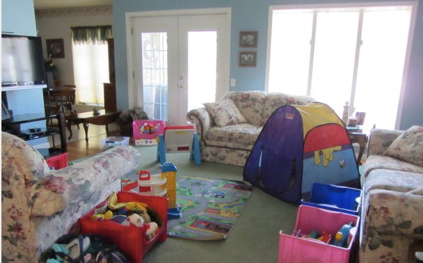 Living room with sofas, a play tent, and toys on the floor