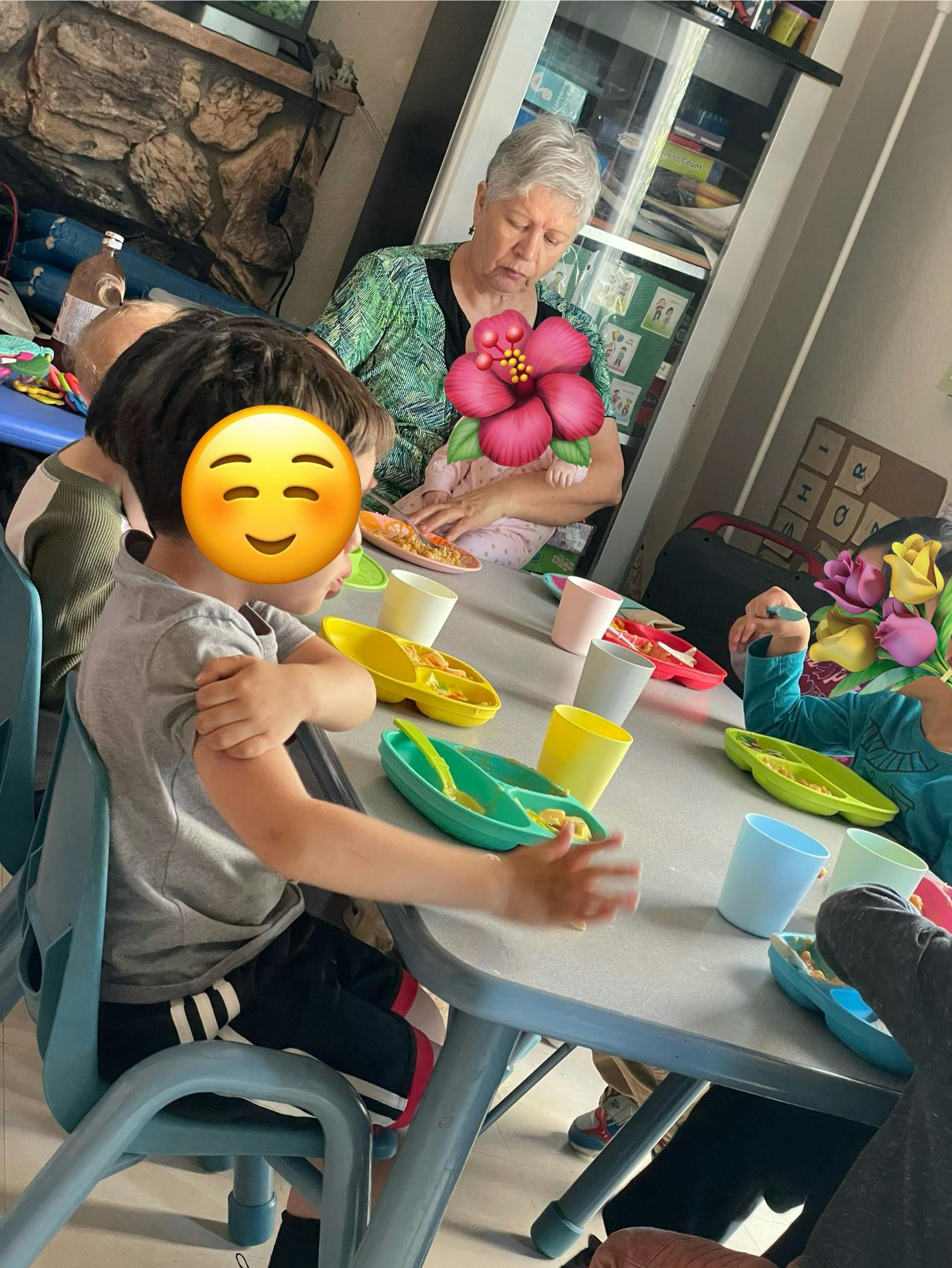 Adult and children sitting at a table with plates and cups