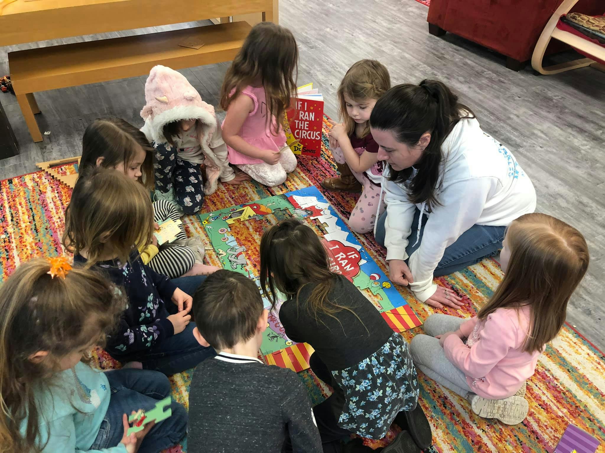 Adult and children sitting on a rug looking at a book