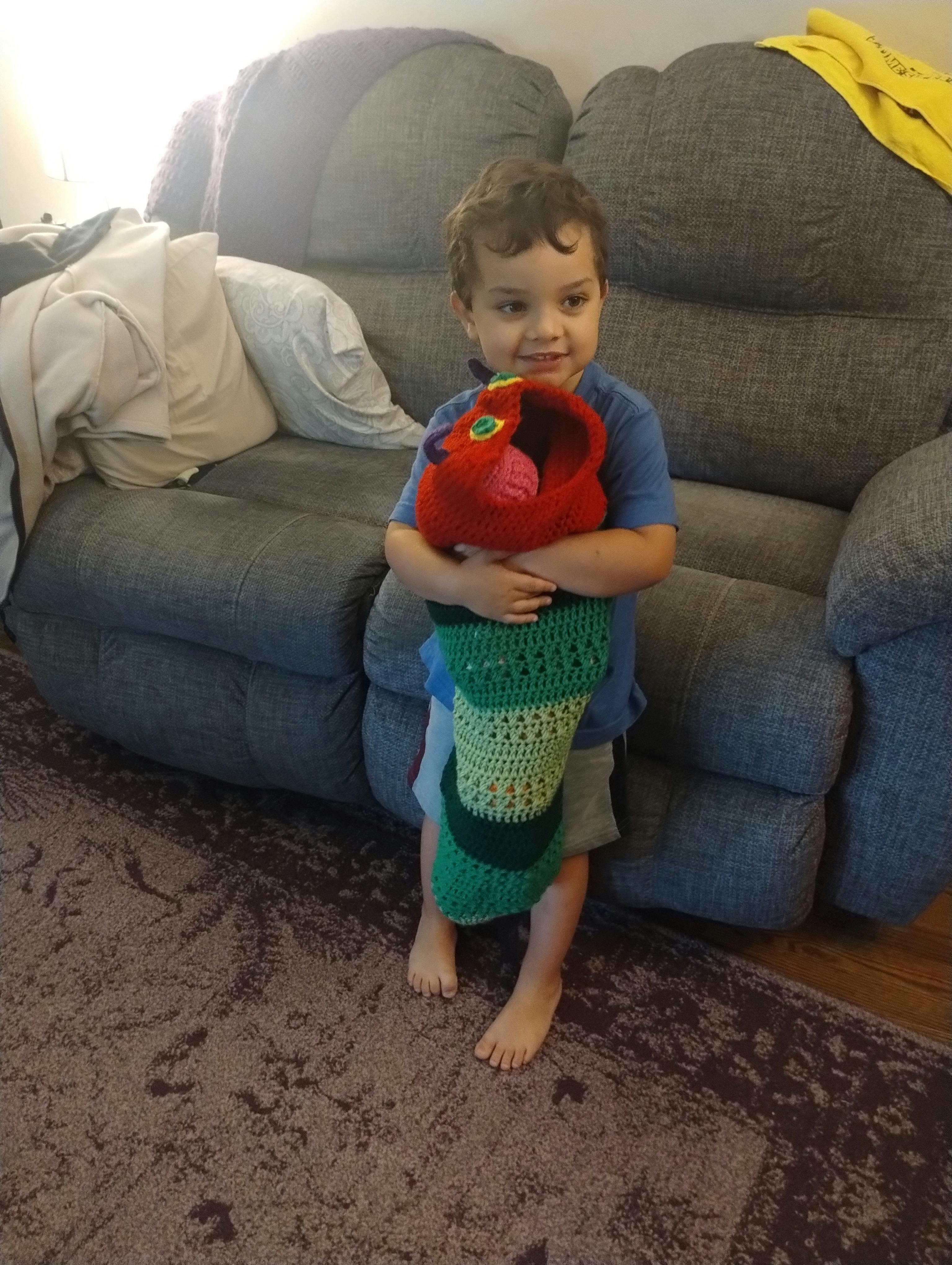 Child holding a crocheted caterpillar toy