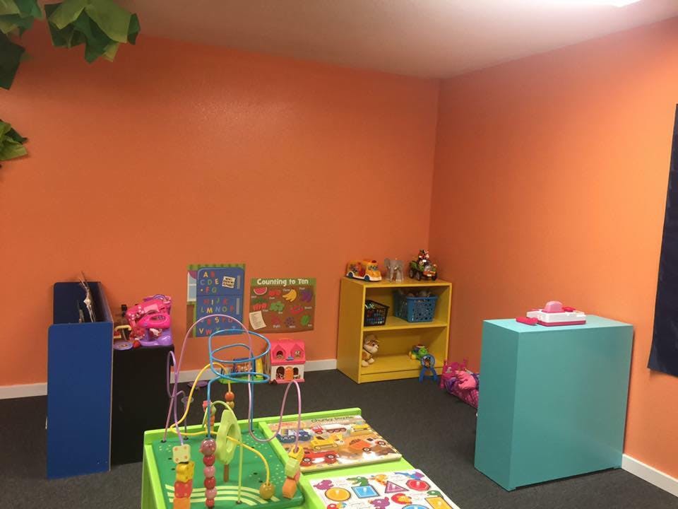 Playroom with orange walls and various toys and furniture