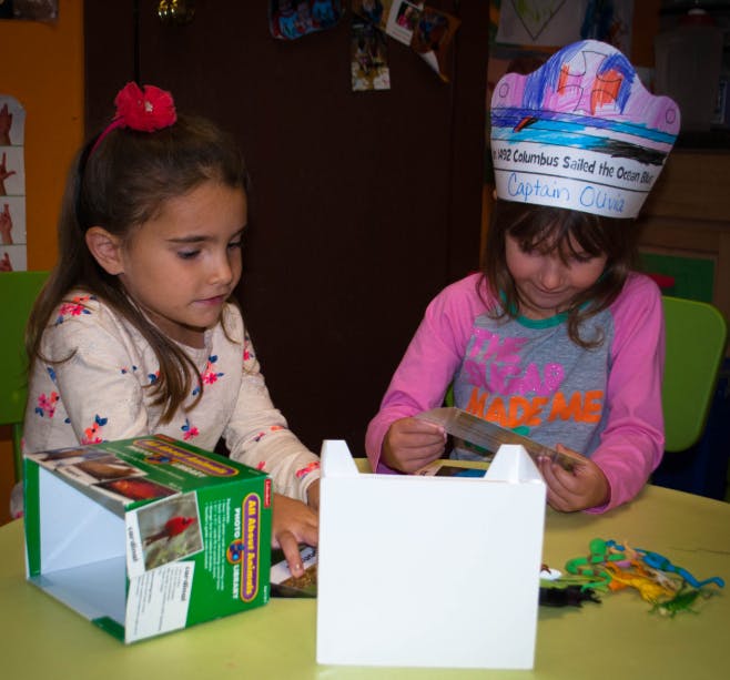 Two children at a table with craft supplies