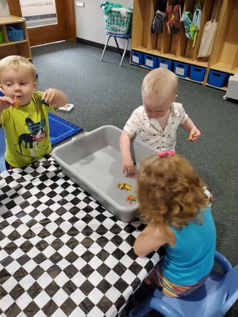 Three children playing with toys in a classroom