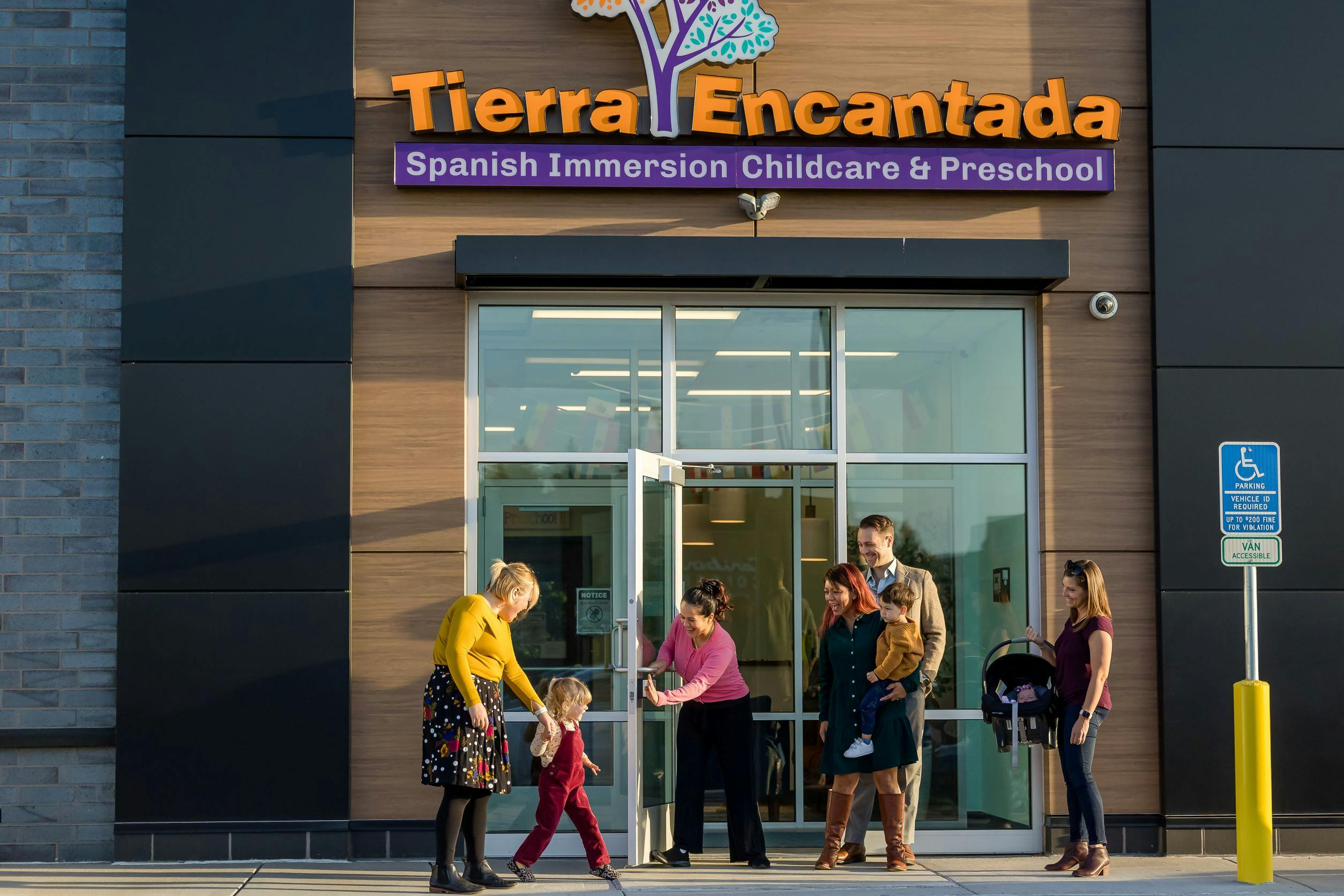 People entering and standing outside a building with a sign for Tierra Encantada