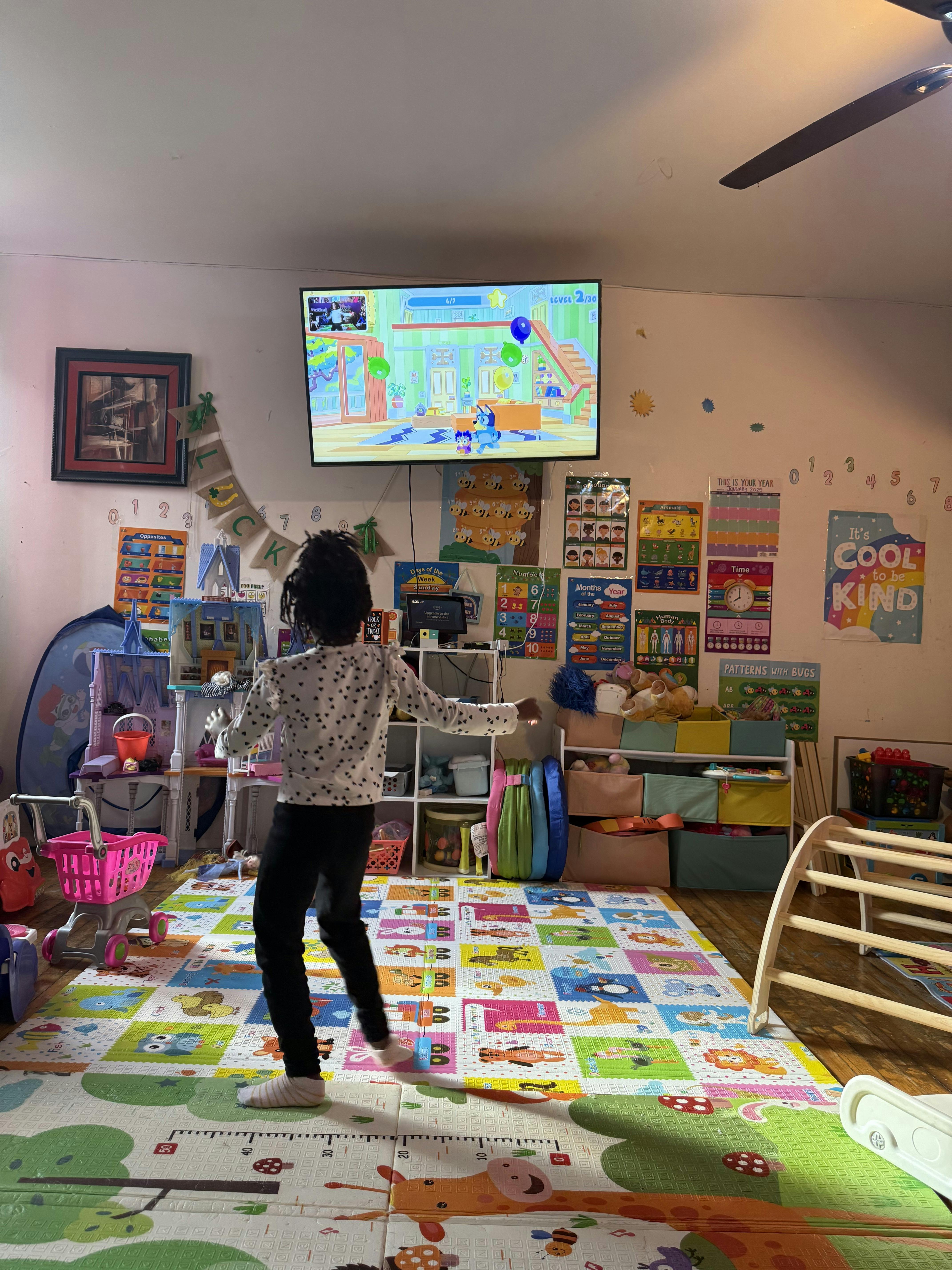Child playing a video game in a room with colorful mats and posters