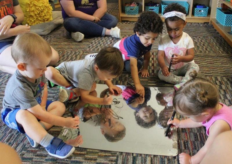 Children drawing on a mirror on the floor