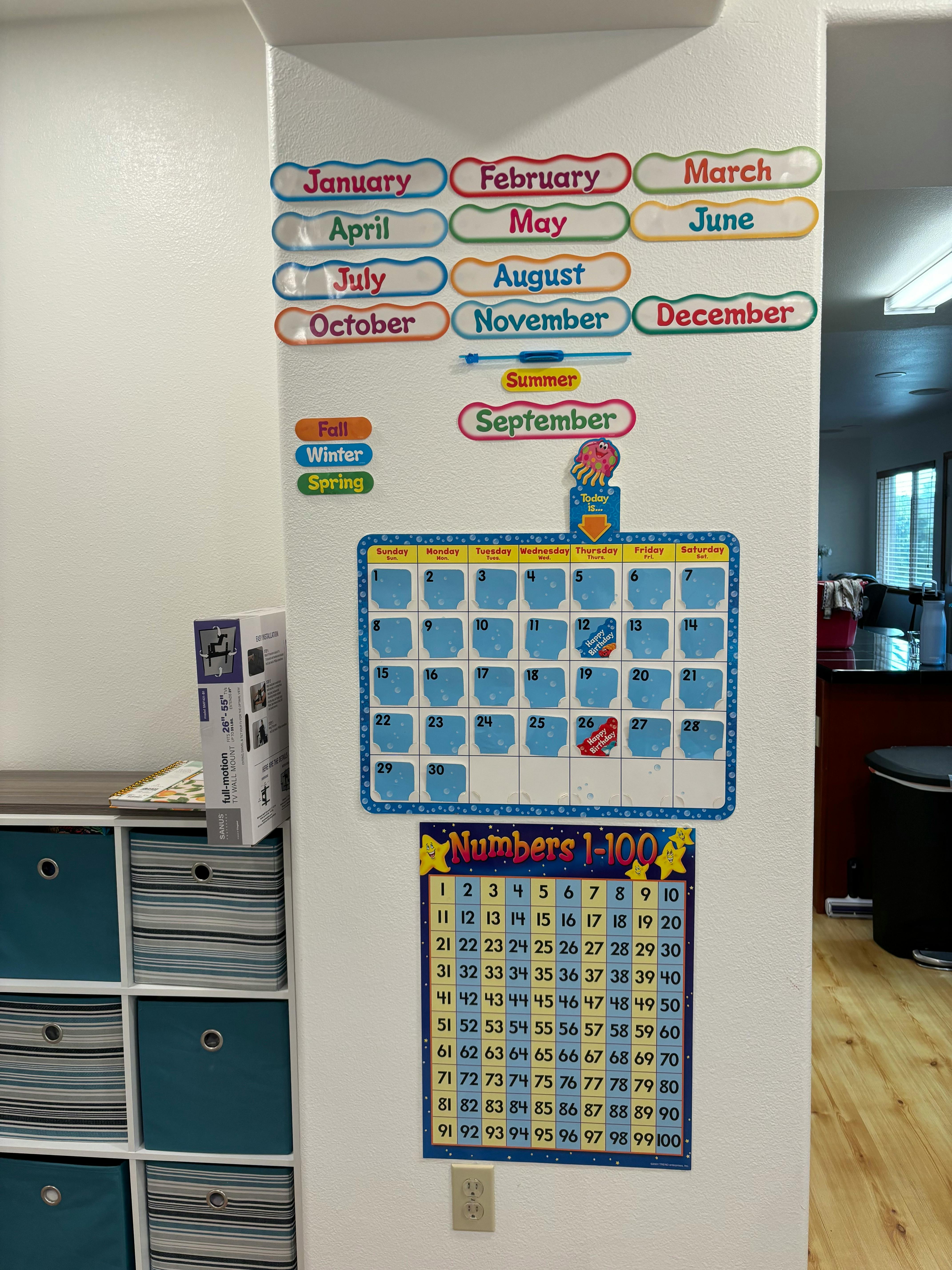 Months of the year, calendar, and numbers 1-100 charts on a wall