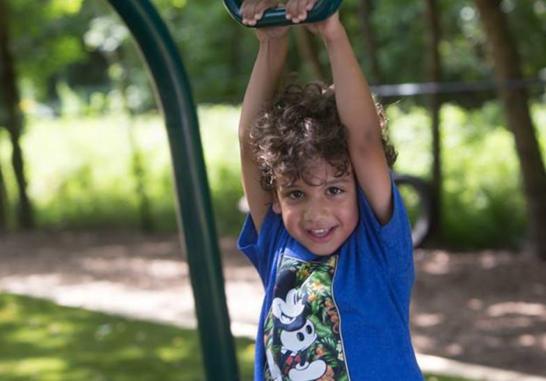 Child hanging from a swing set bar