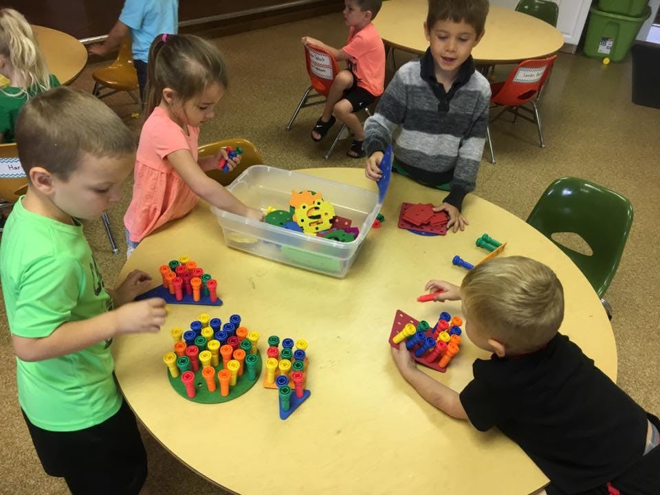 Children playing with colorful building toys at a round table