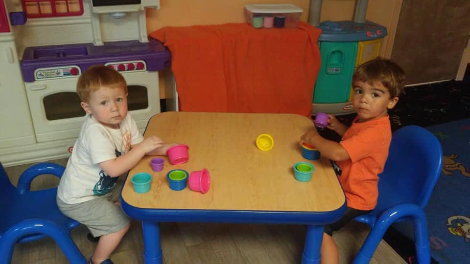 Two children playing with colorful cups at a small table