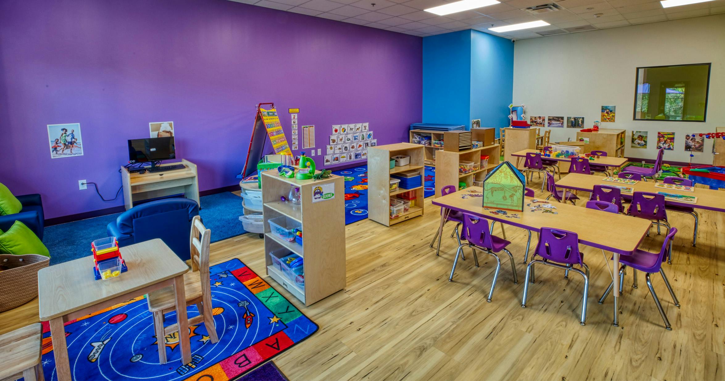 Colorful empty classroom with small tables, chairs, and learning materials
