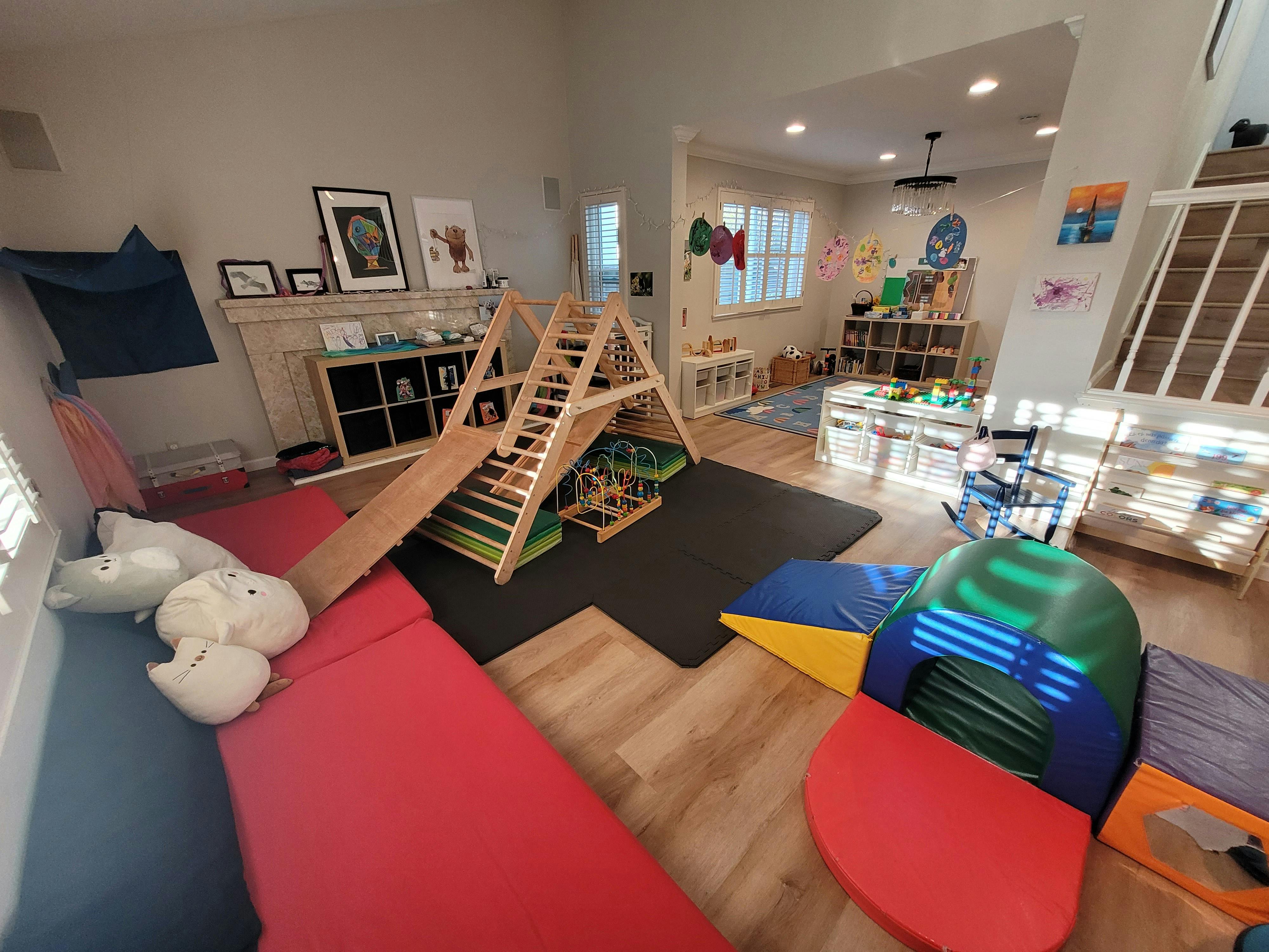 Indoor play area with a wooden climbing structure and soft mats