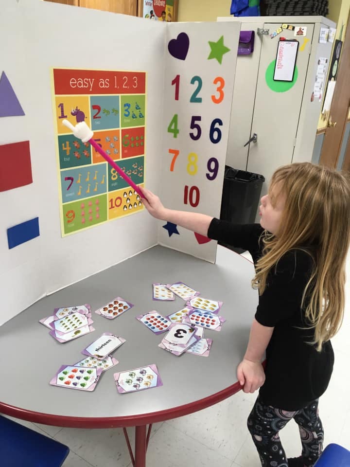 Child pointing to a number chart with a pointer