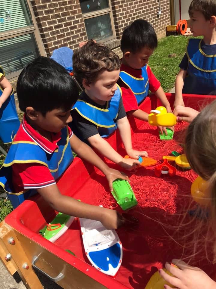 Children playing with toys in a red water table