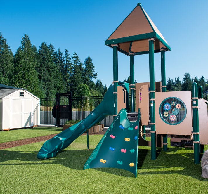 Playground with slide and climbing wall on artificial turf