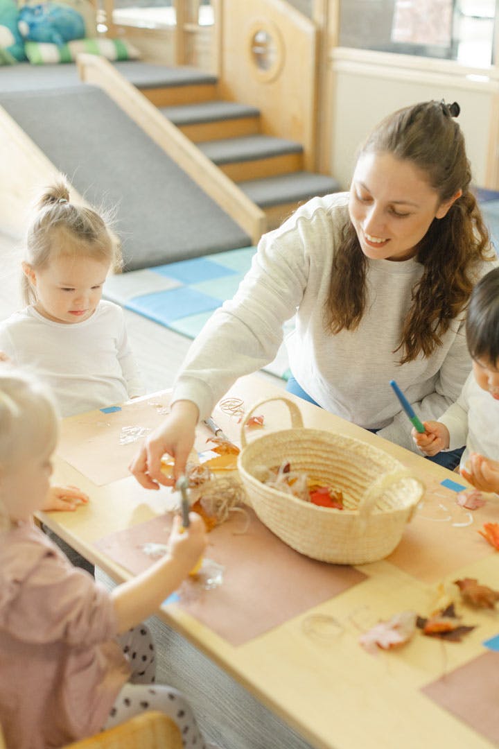 Adult and children crafting with leaves at a table