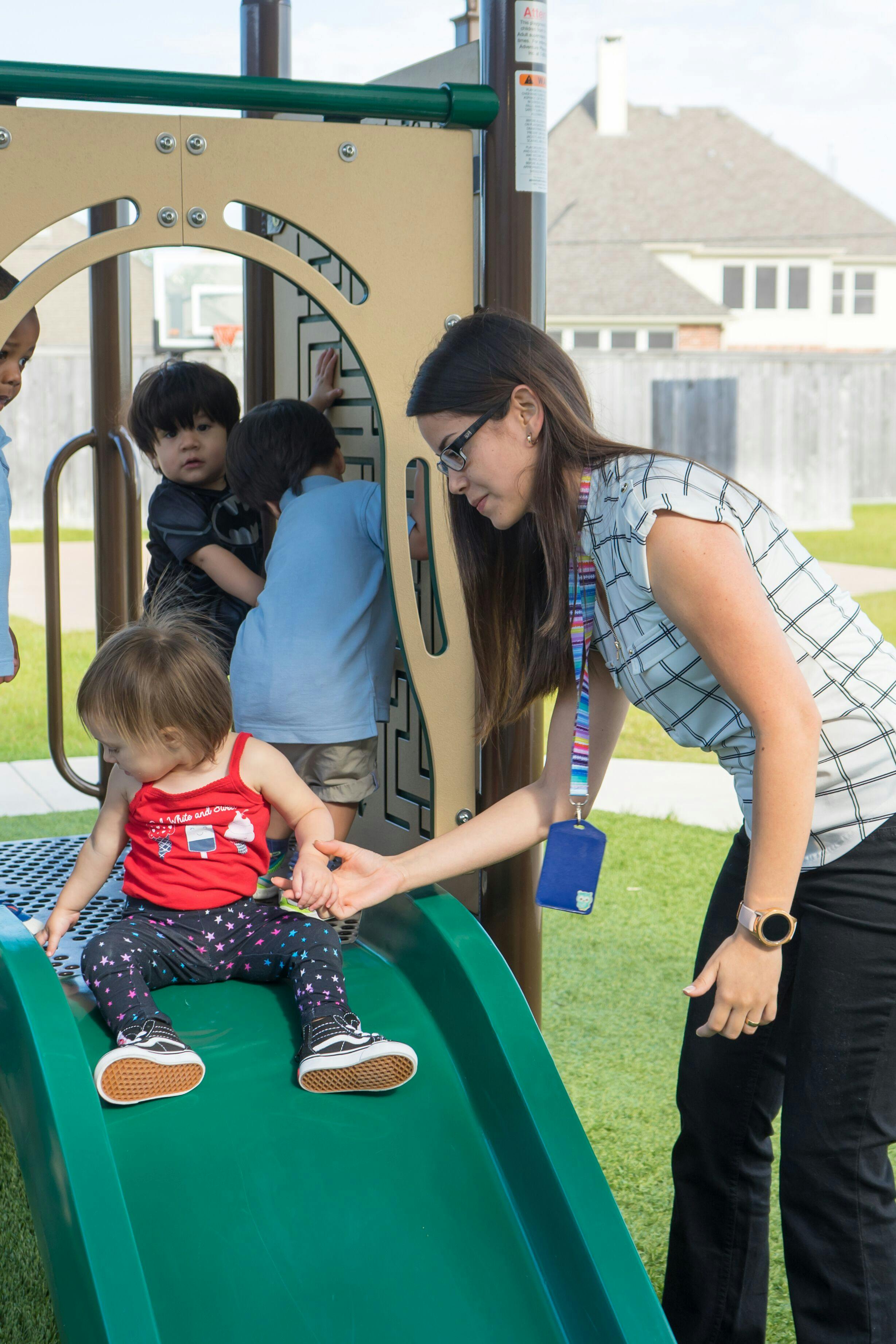 Adult helping a child on a playground slide