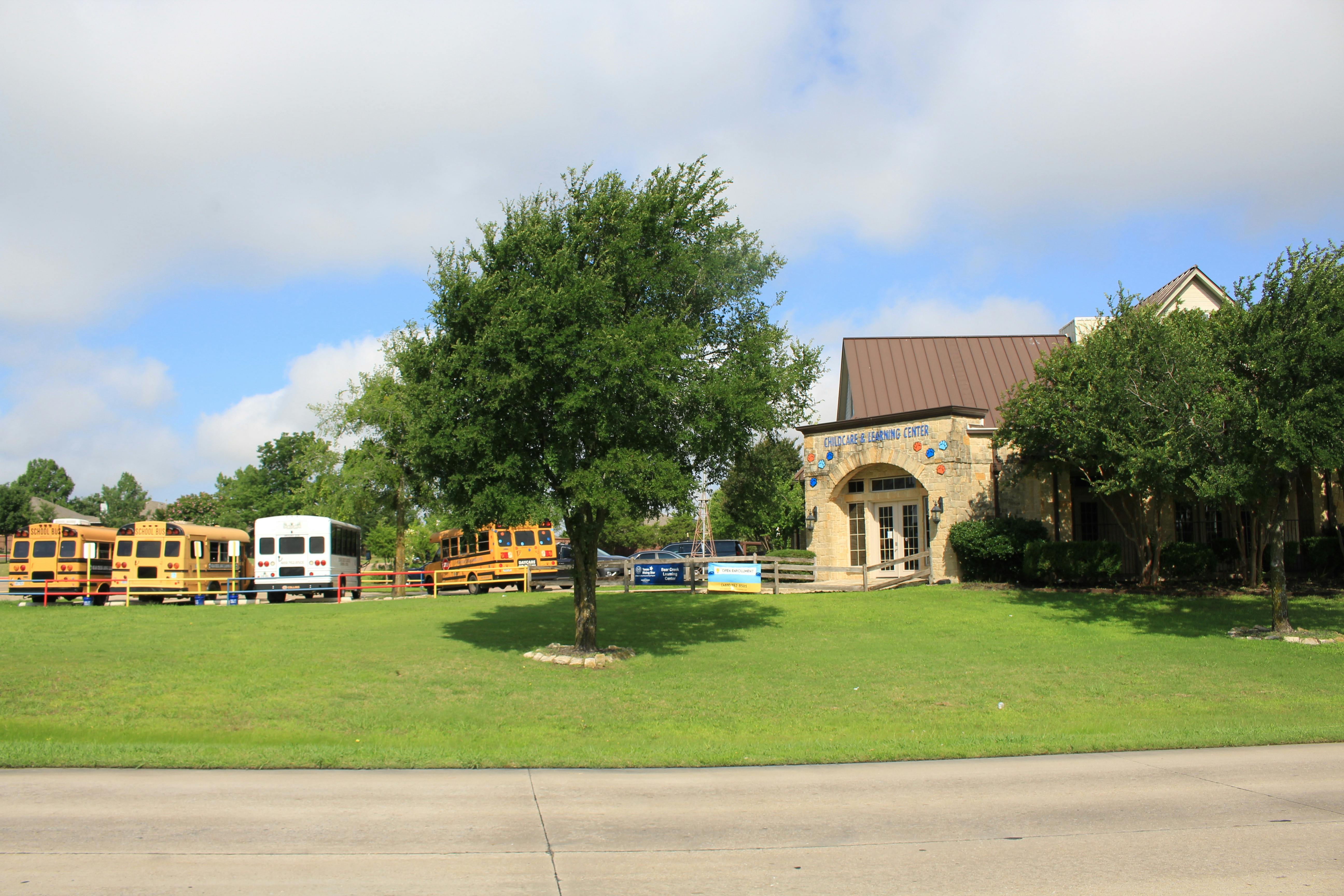 Building with arched entrance and multiple school buses parked on grass