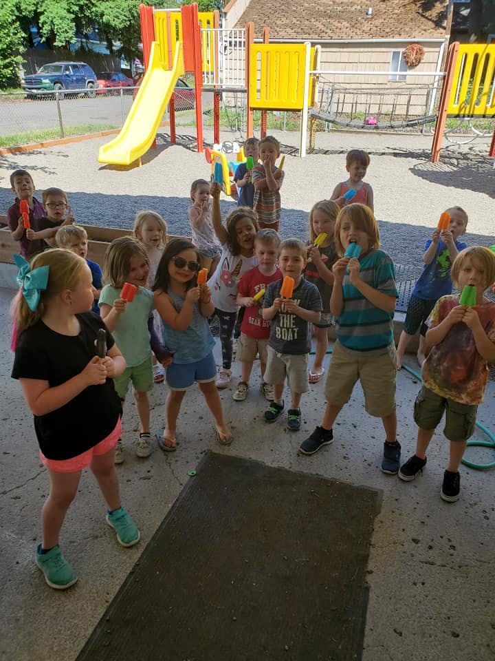 Group of children eating popsicles on a playground