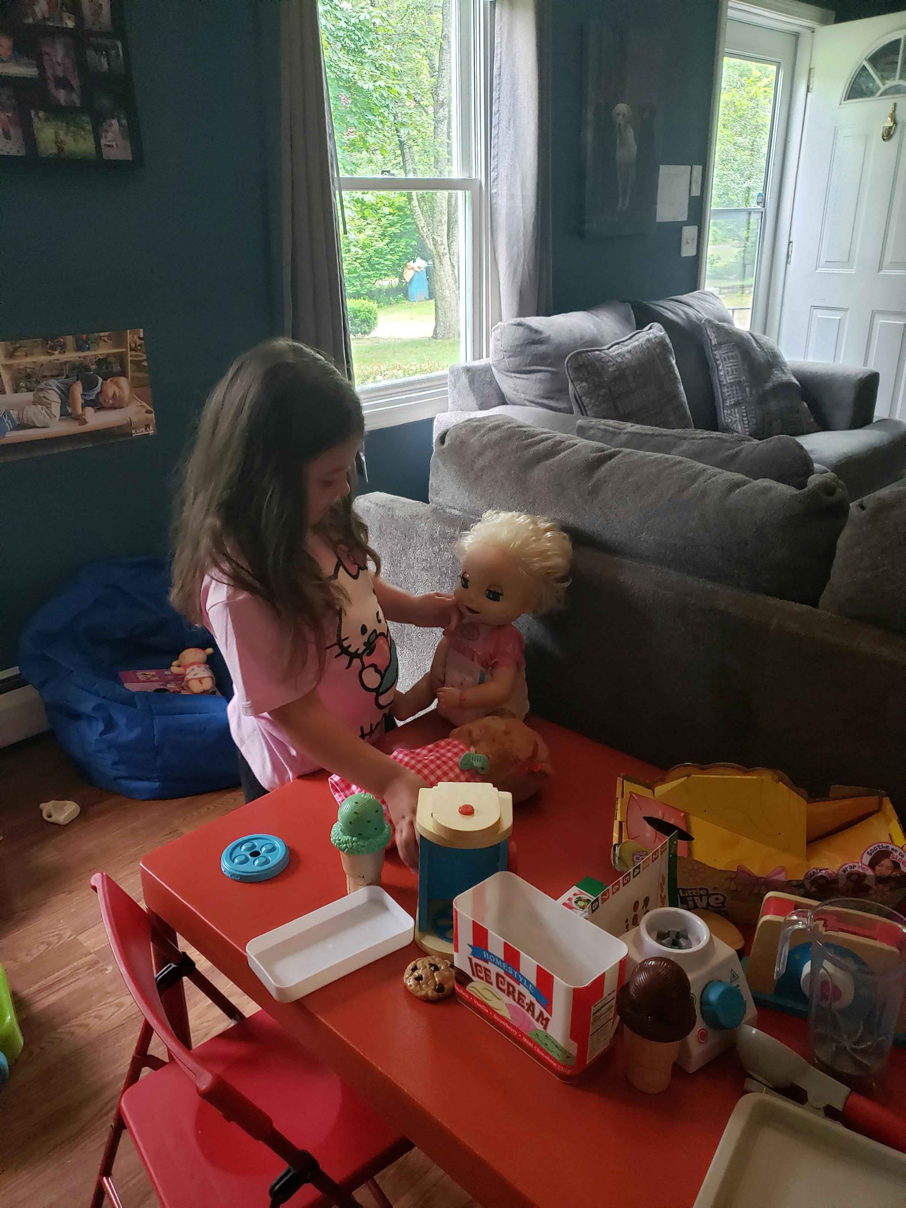 Child playing with a doll and toy food on a red table