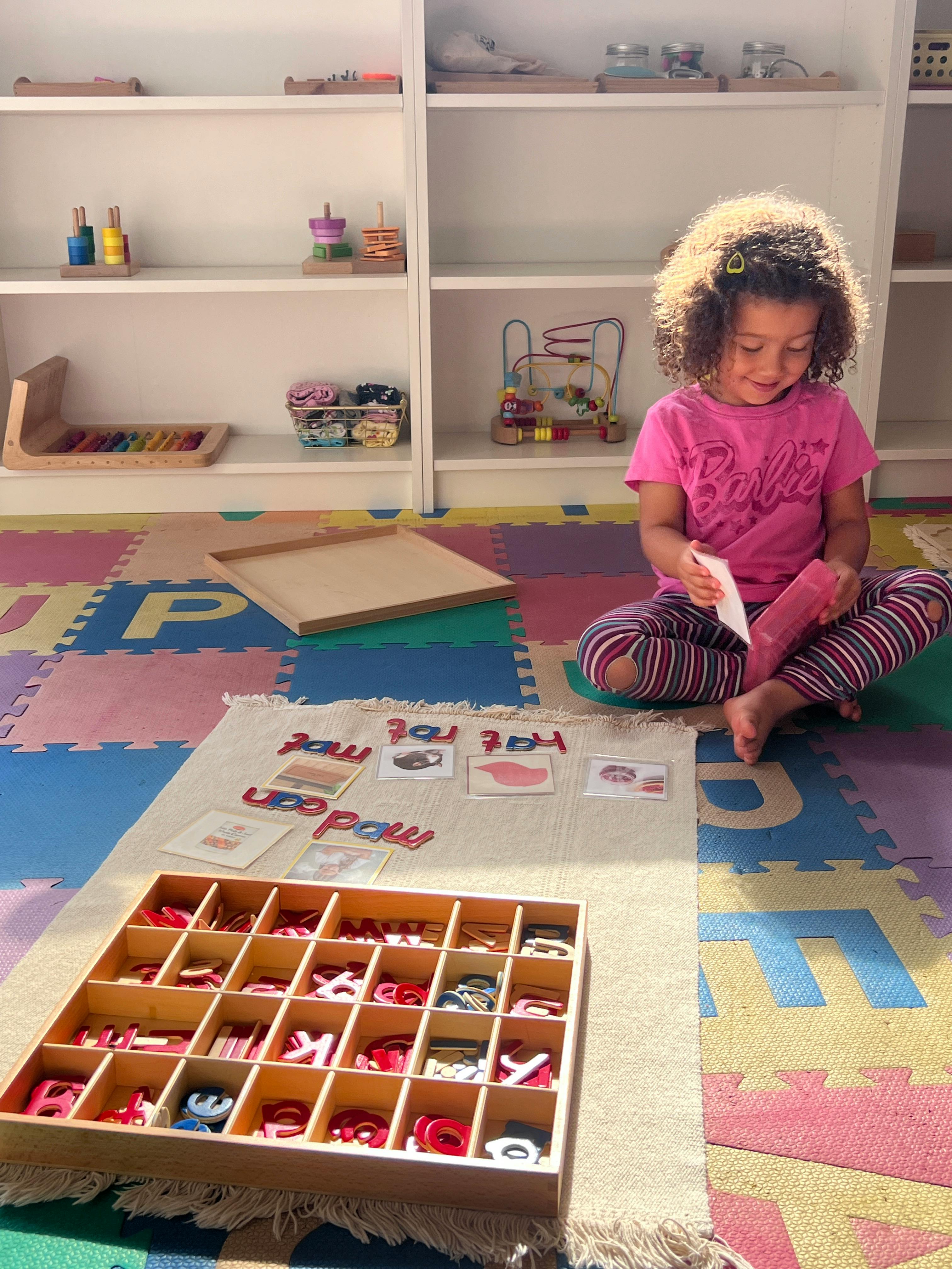 Child sitting on floor with letter tiles and picture cards