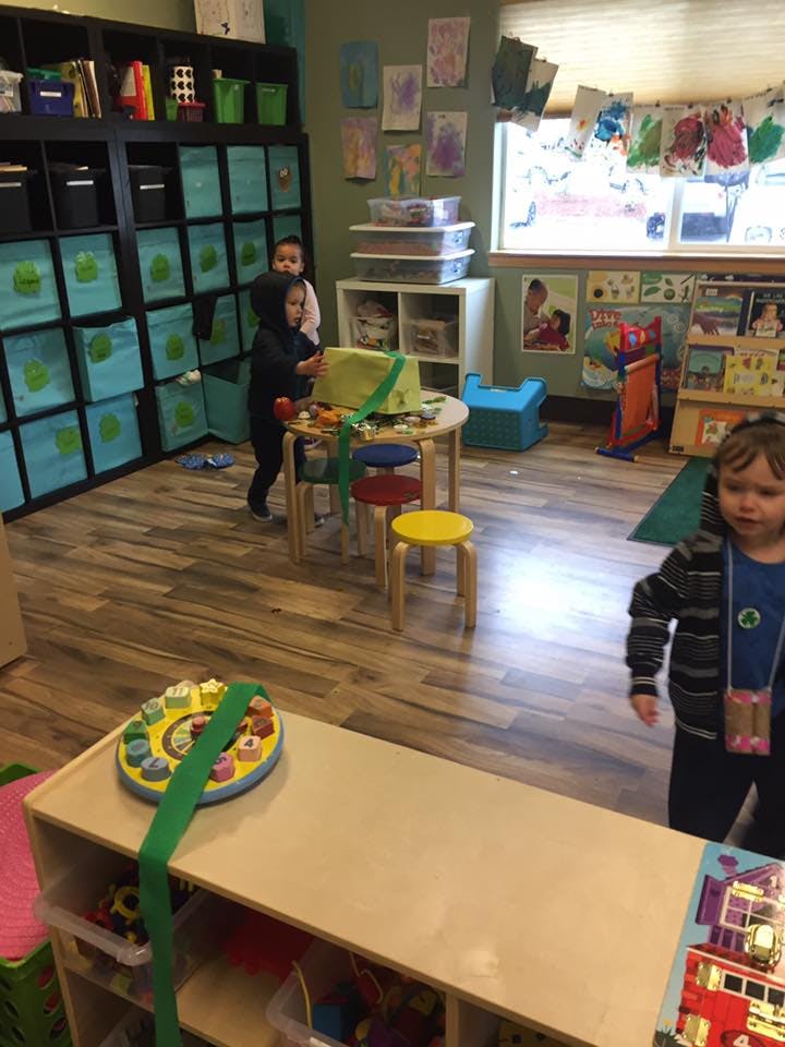 Two children playing with toys at a small table in a classroom