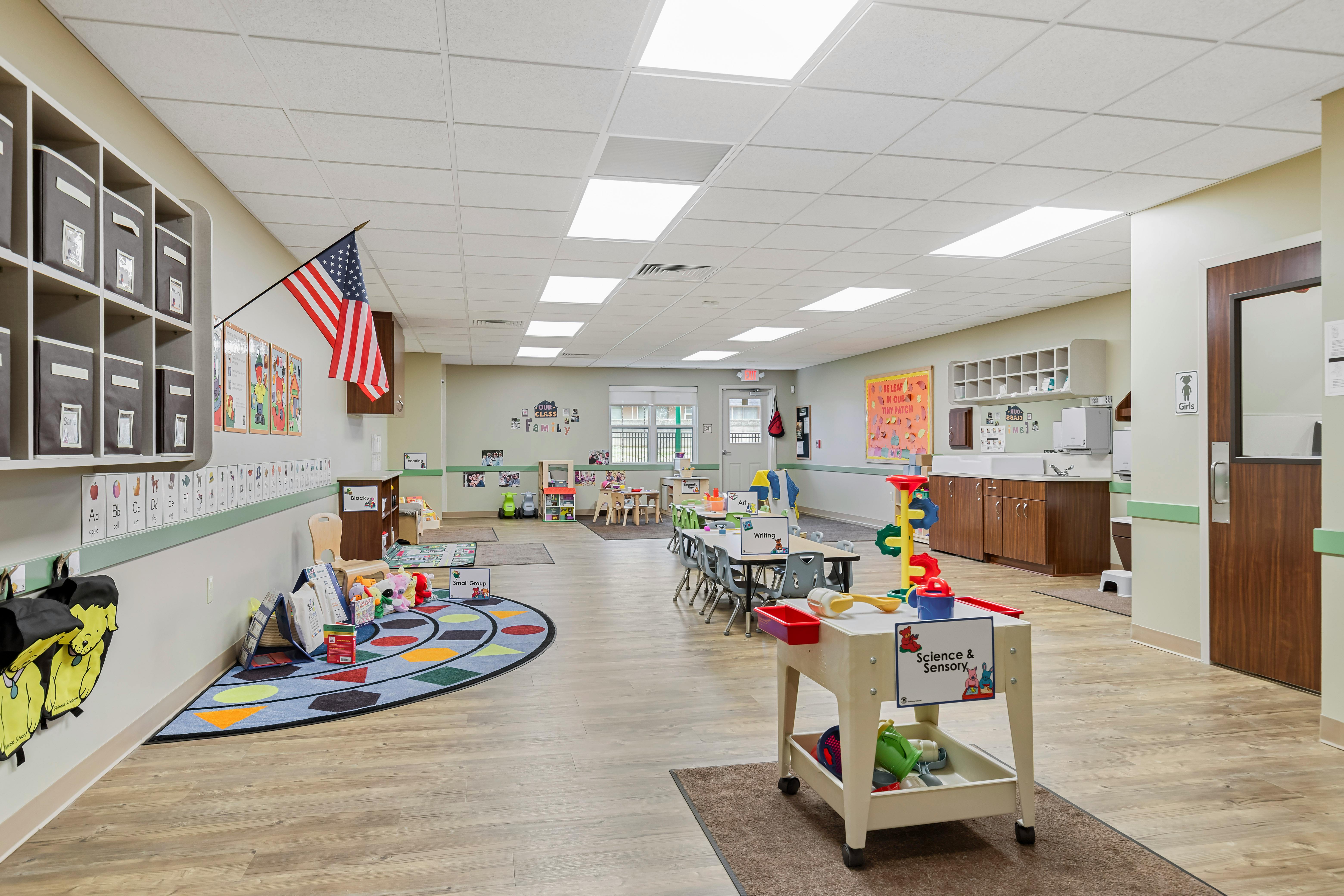 Classroom with cubbies, an American flag, children's tables and chairs