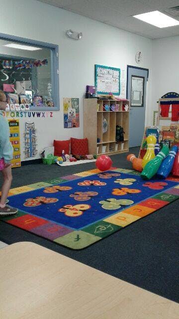 Child standing on a colorful rug in a classroom