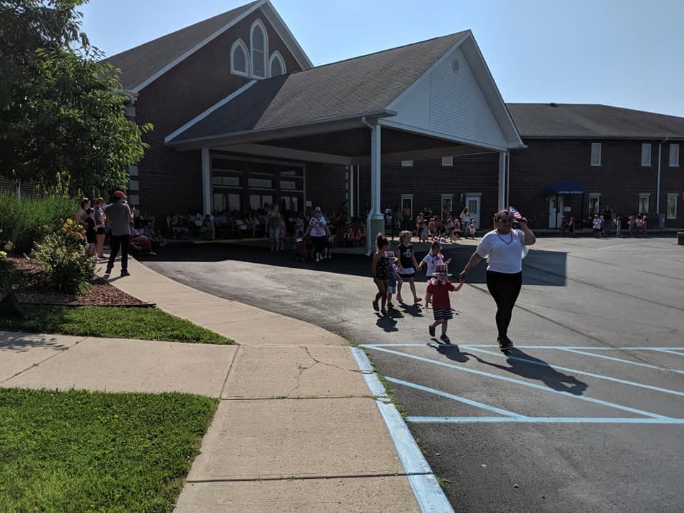 Adult and children walking on pavement in front of a building