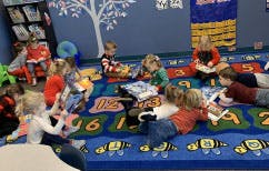 Children sitting on a rug in a classroom