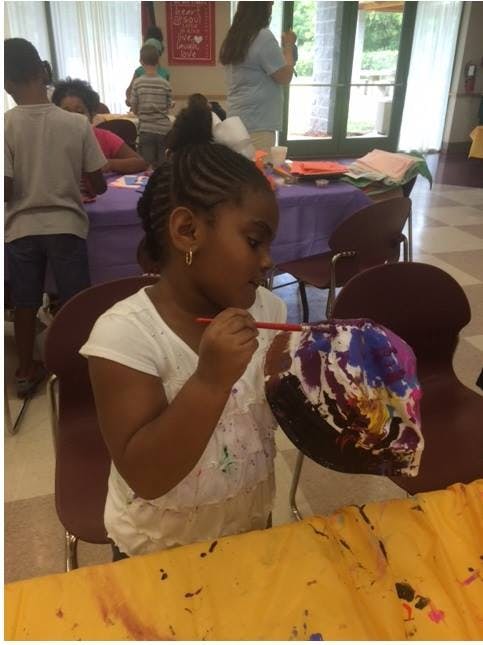 Child painting a colorful object with a paintbrush