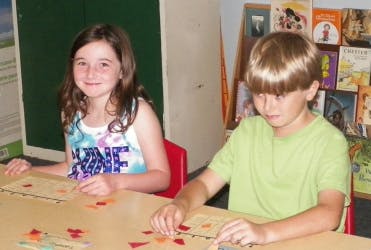 Two children at a table with craft materials
